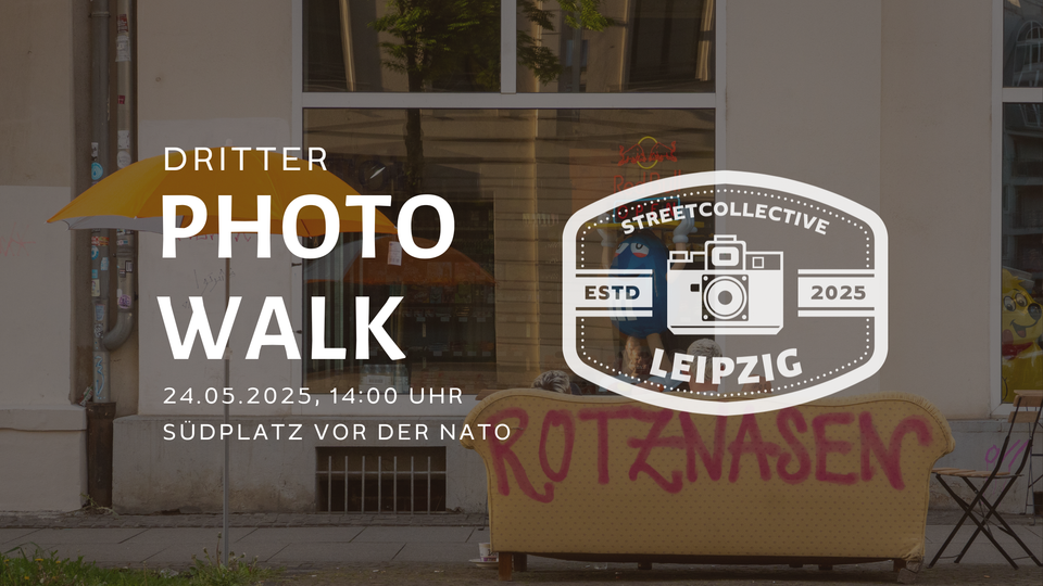 Blick auf die Rückseite einer Couch auf der Rotznasen steht. Neben einem Sonnenschirm vor einer Fassade.
